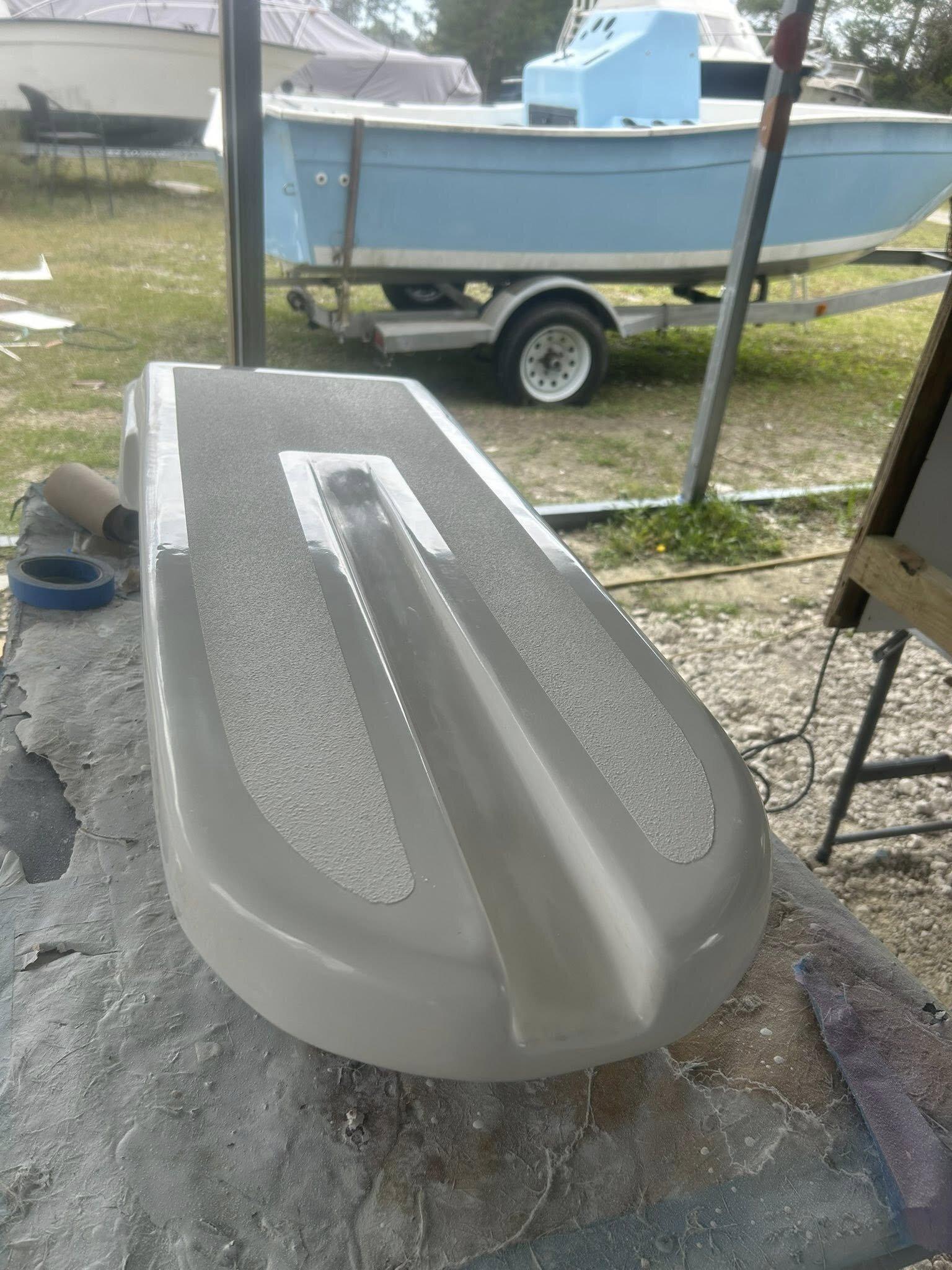 Refinished outboard cowling on the bench in factory-match silver with contrasting textured non-skid panels, ready to reinstall