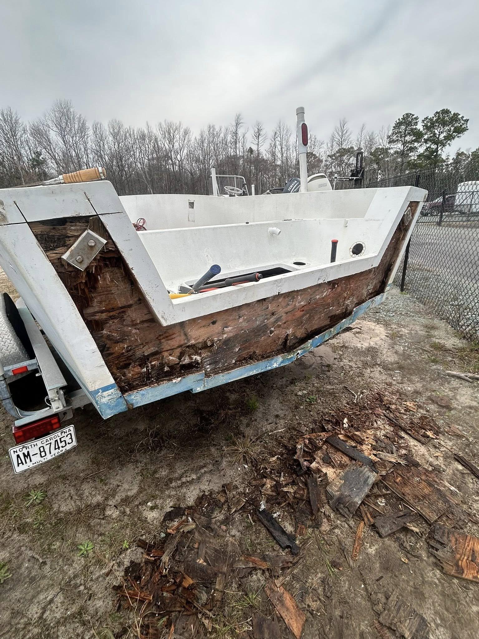 Hull on trailer showing a rotted transom core with exposed wood failure before structural rebuild